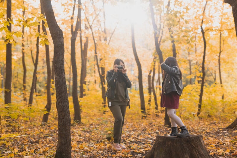 Mom photographing her daughter in a forest